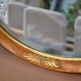 Old oval beveled wooden mirror, partly gilded and carved