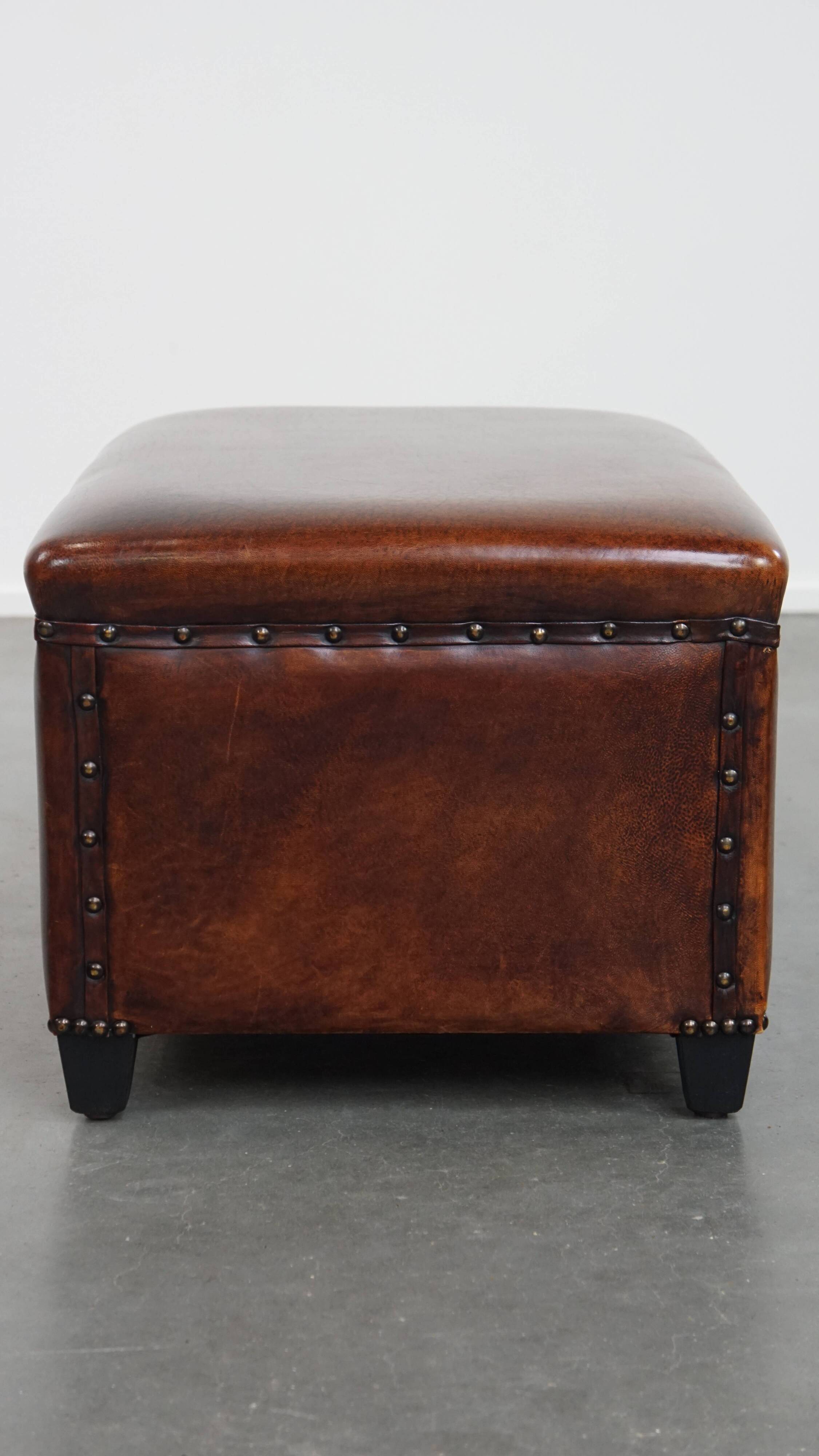Cognac-colored sheepskin stool with decorative studs