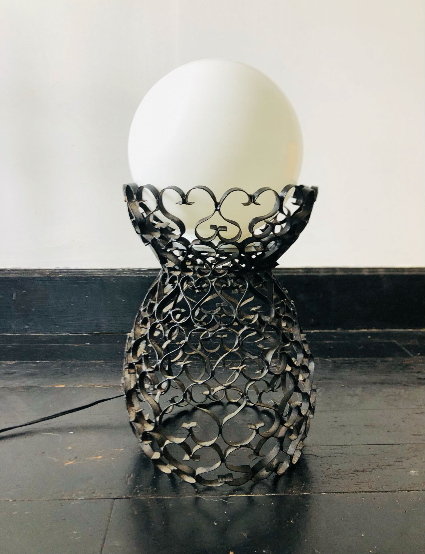 Handcrafted wrought iron lamp with a white opaline globe.