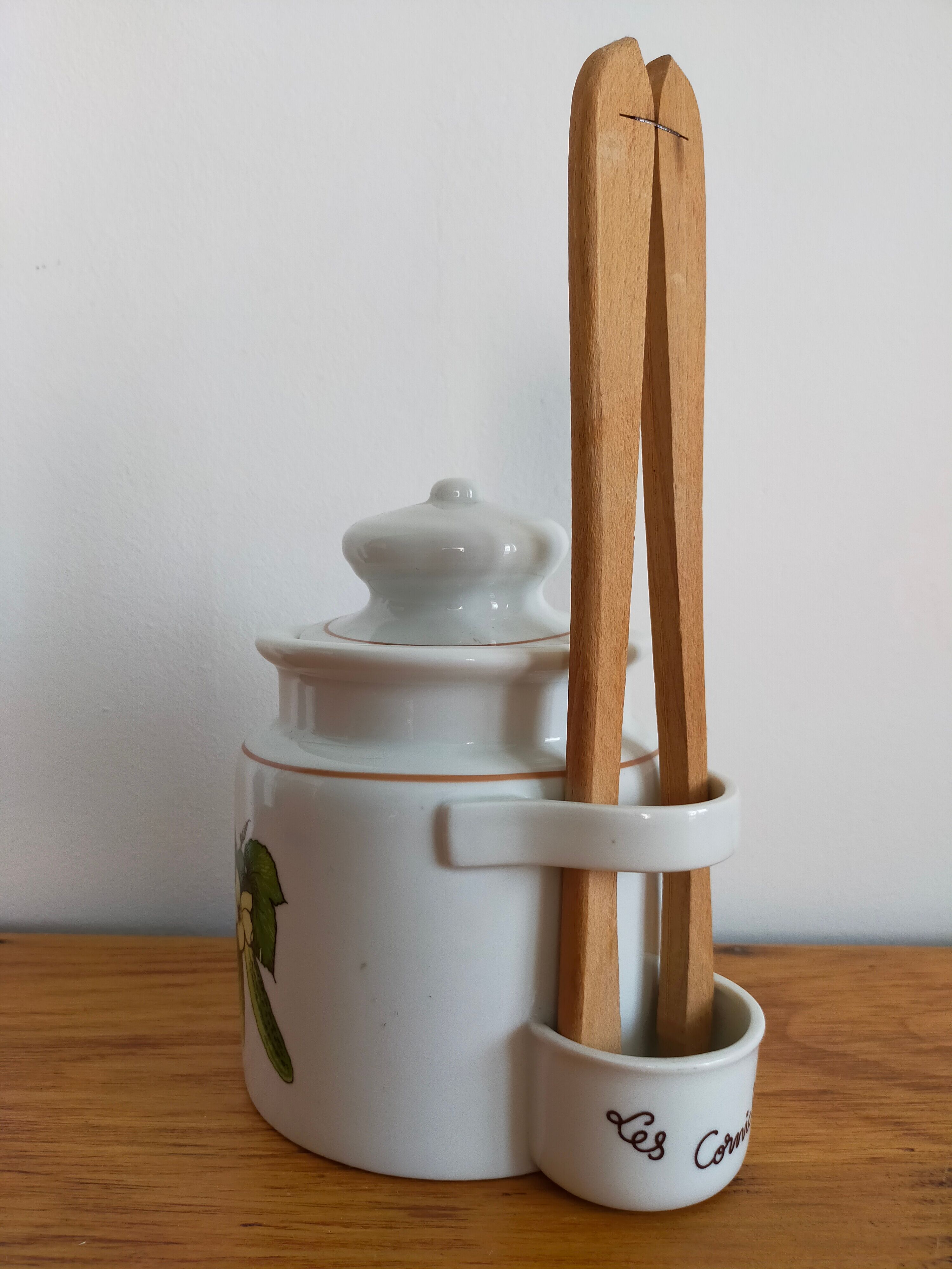Vintage porcelain pickle pot with wooden pliers.