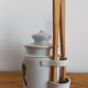 Vintage porcelain pickle pot with wooden pliers.