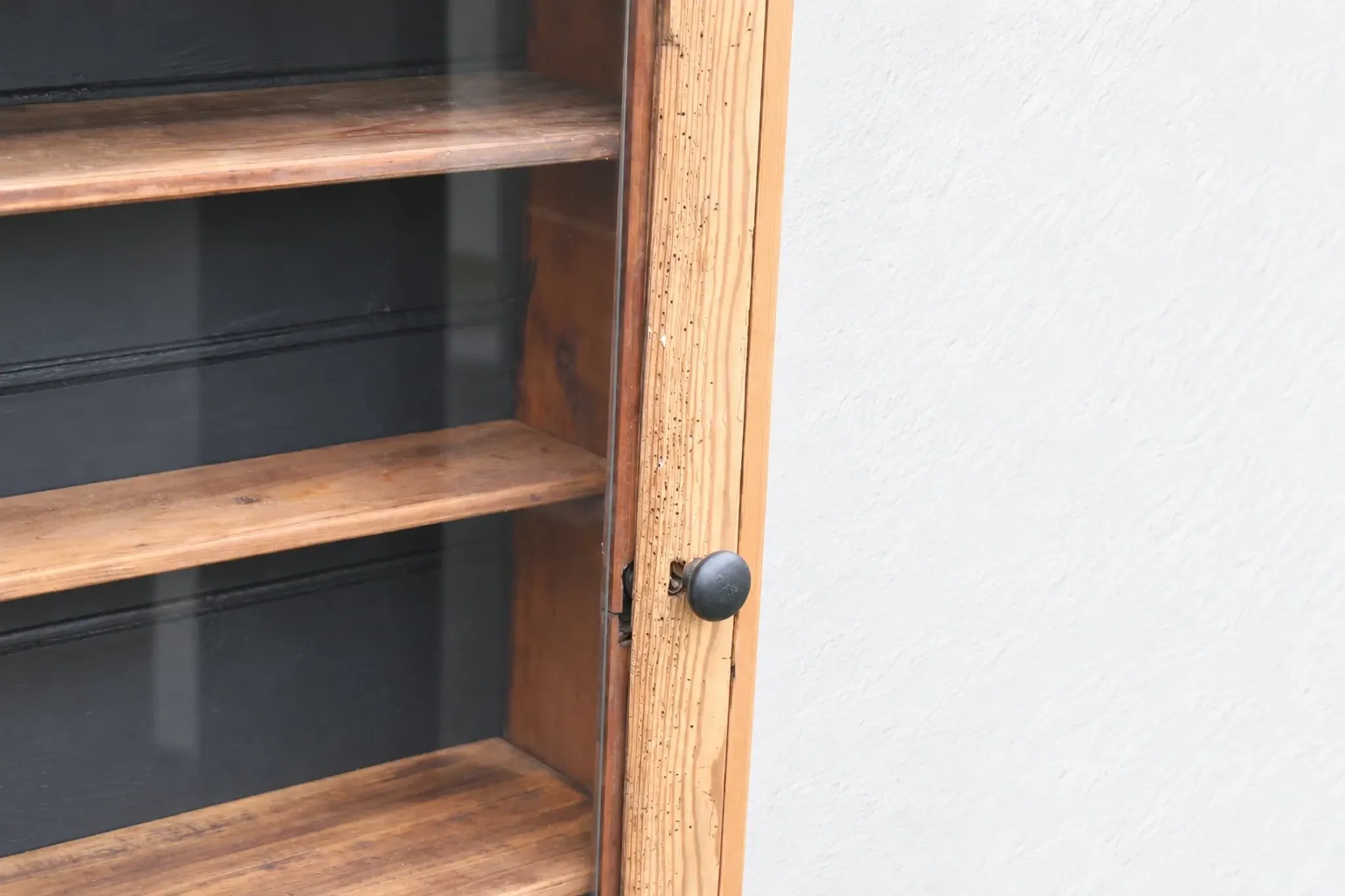 Antique wall display cabinet in natural wood and black – small glass-fronted collector's piece.