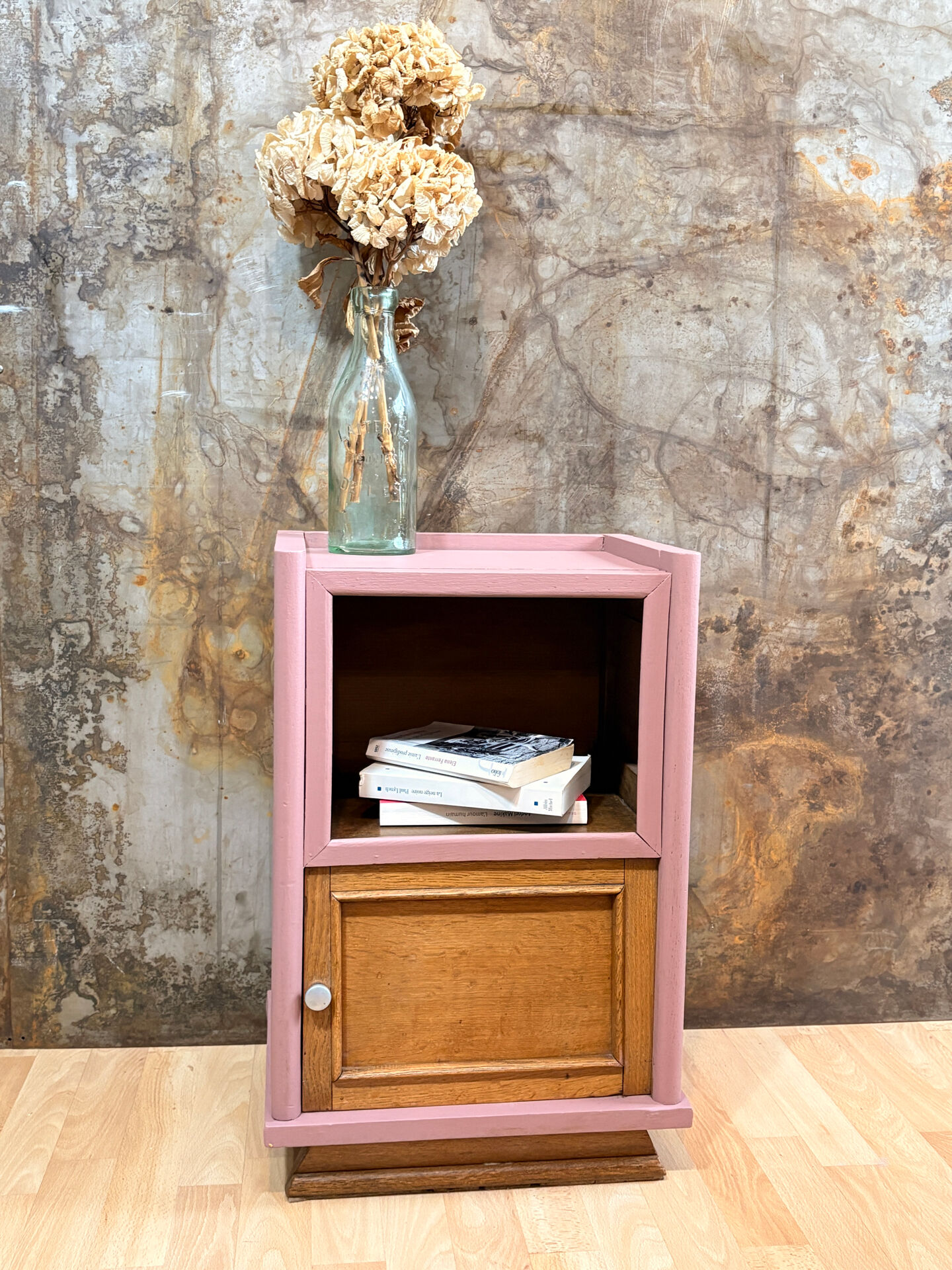 Pink bedside table with haberdashery and raw wood.