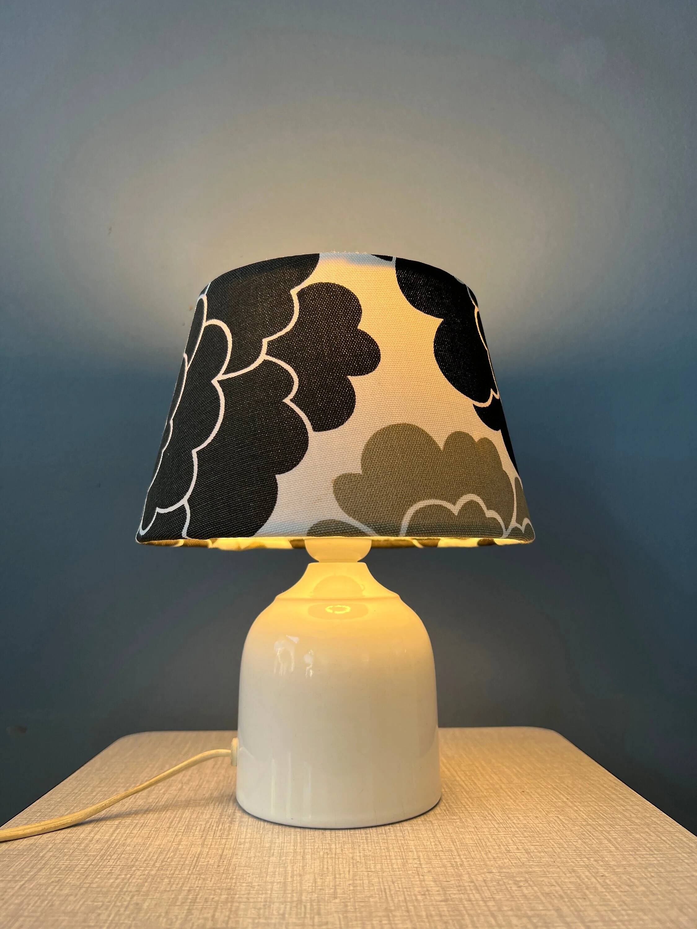 Small Space Age table lamp with a porcelain base and black and white flower shade.