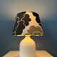 Small Space Age table lamp with a porcelain base and black and white flower shade.