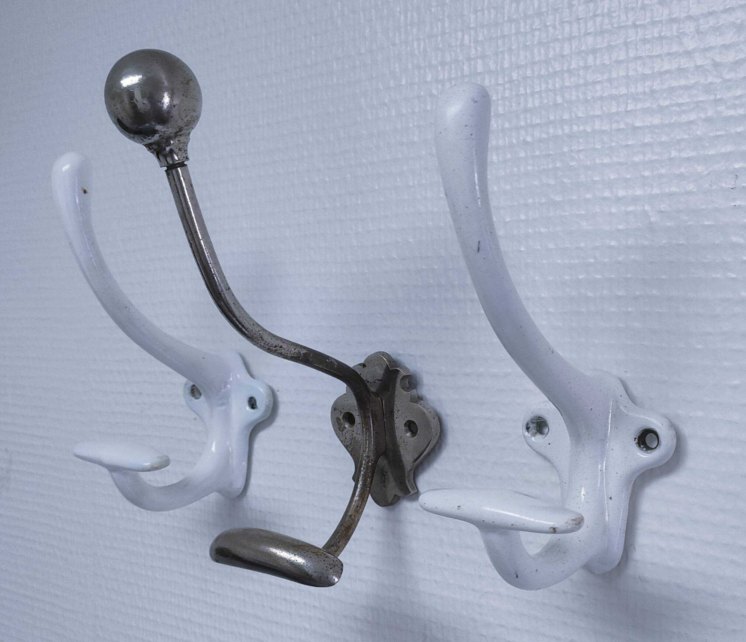 Three enameled cast iron coat hooks and vintage patina metal