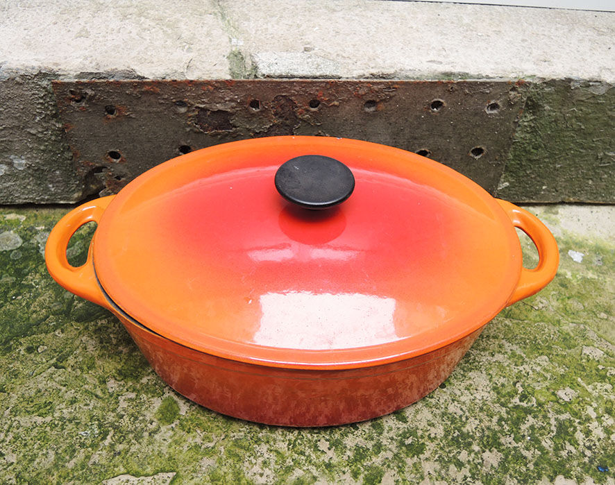 Old oval casserole in orange enamelled cast iron