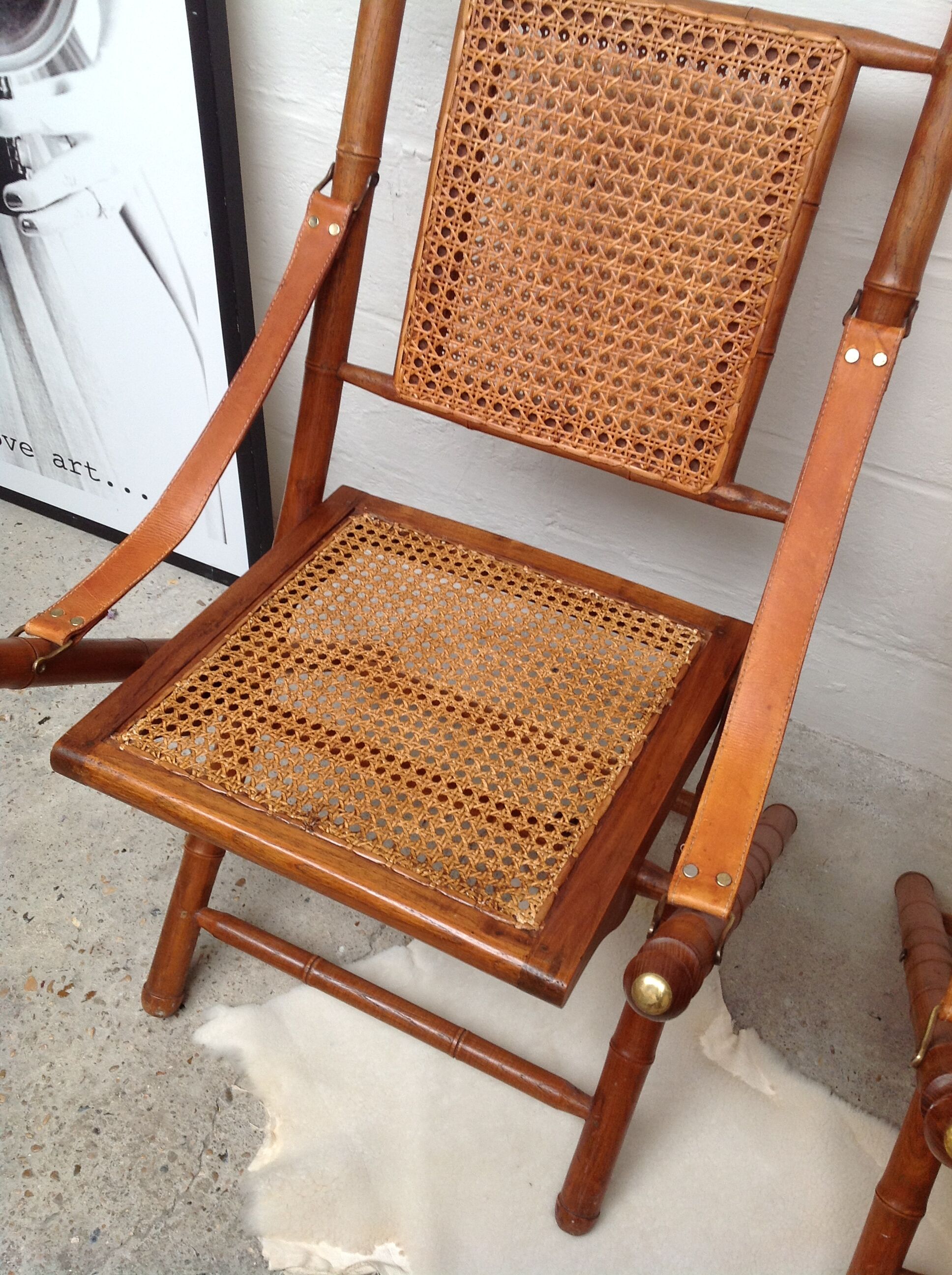 Pair of folding chairs in bamboo and caning, leather and brass