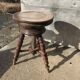 Adjustable brown leather piano stool with turned legs, produced in the 1940s.