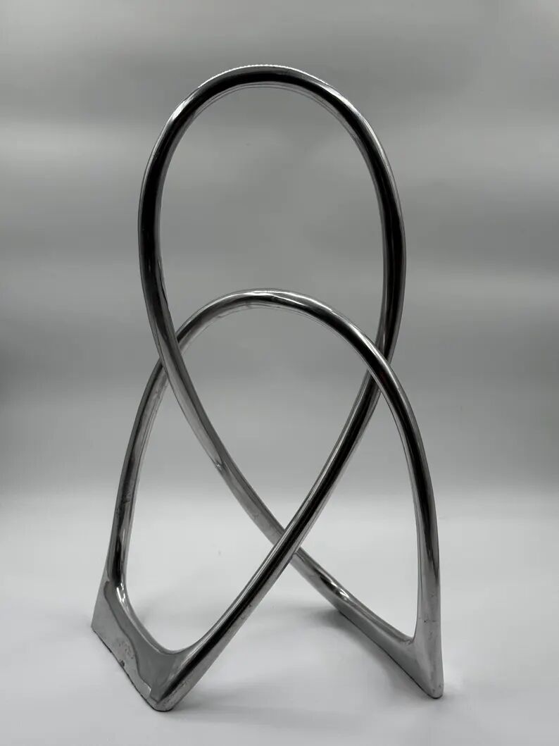 Chromed sculptural art object, abstract modernist shape in metal, contemporary design accent, brutalist interior decoration.