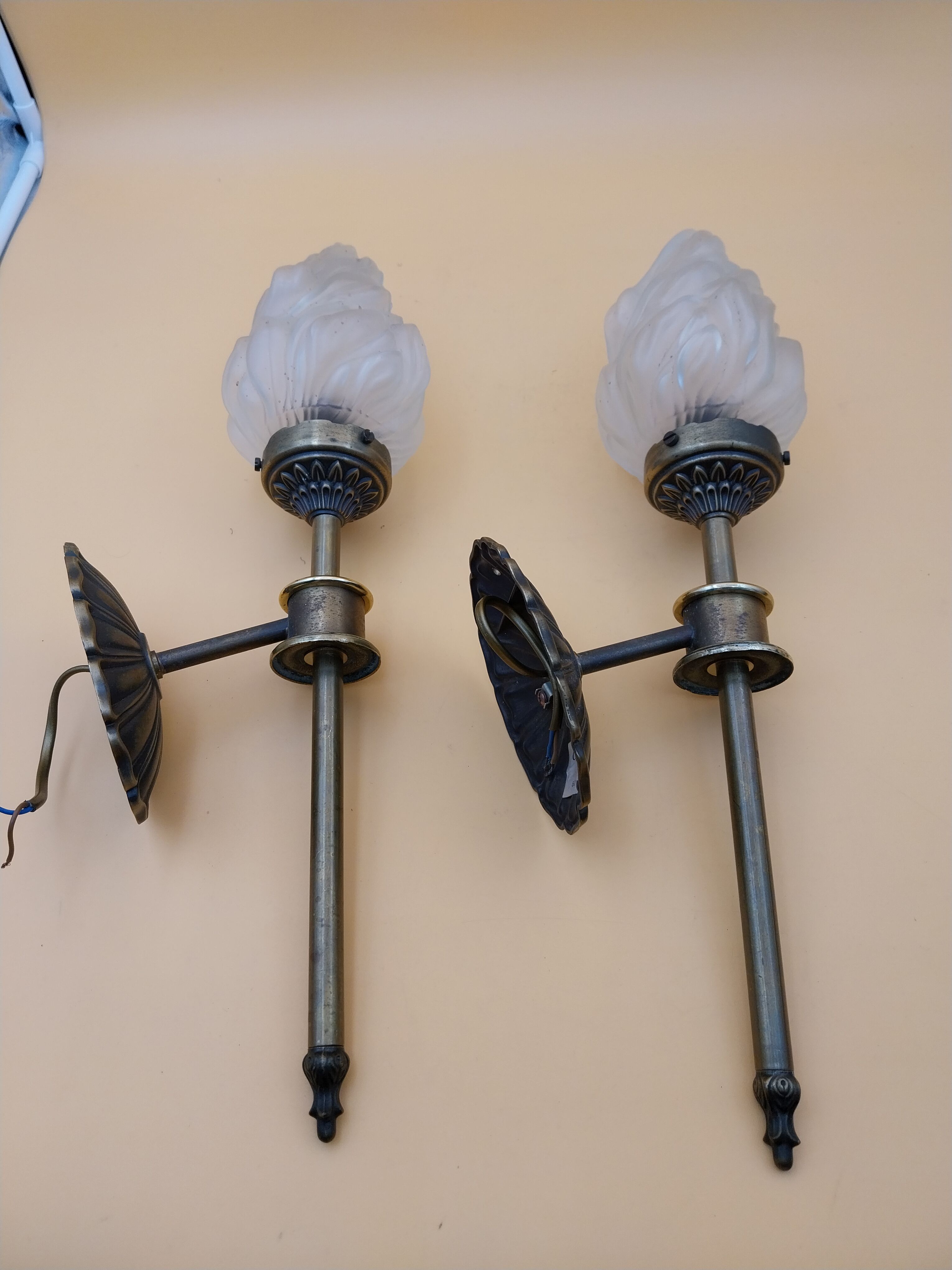 Pair of brass torch wall lights with globe flame.