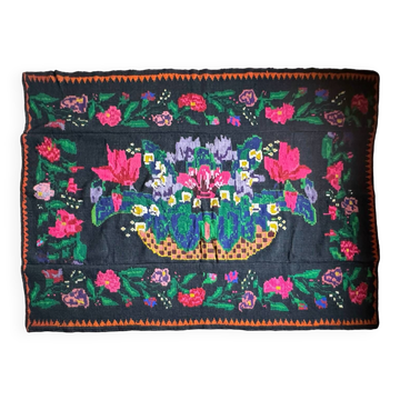 Tapis noir en laine roumain avec un panier de fleurs colorées.