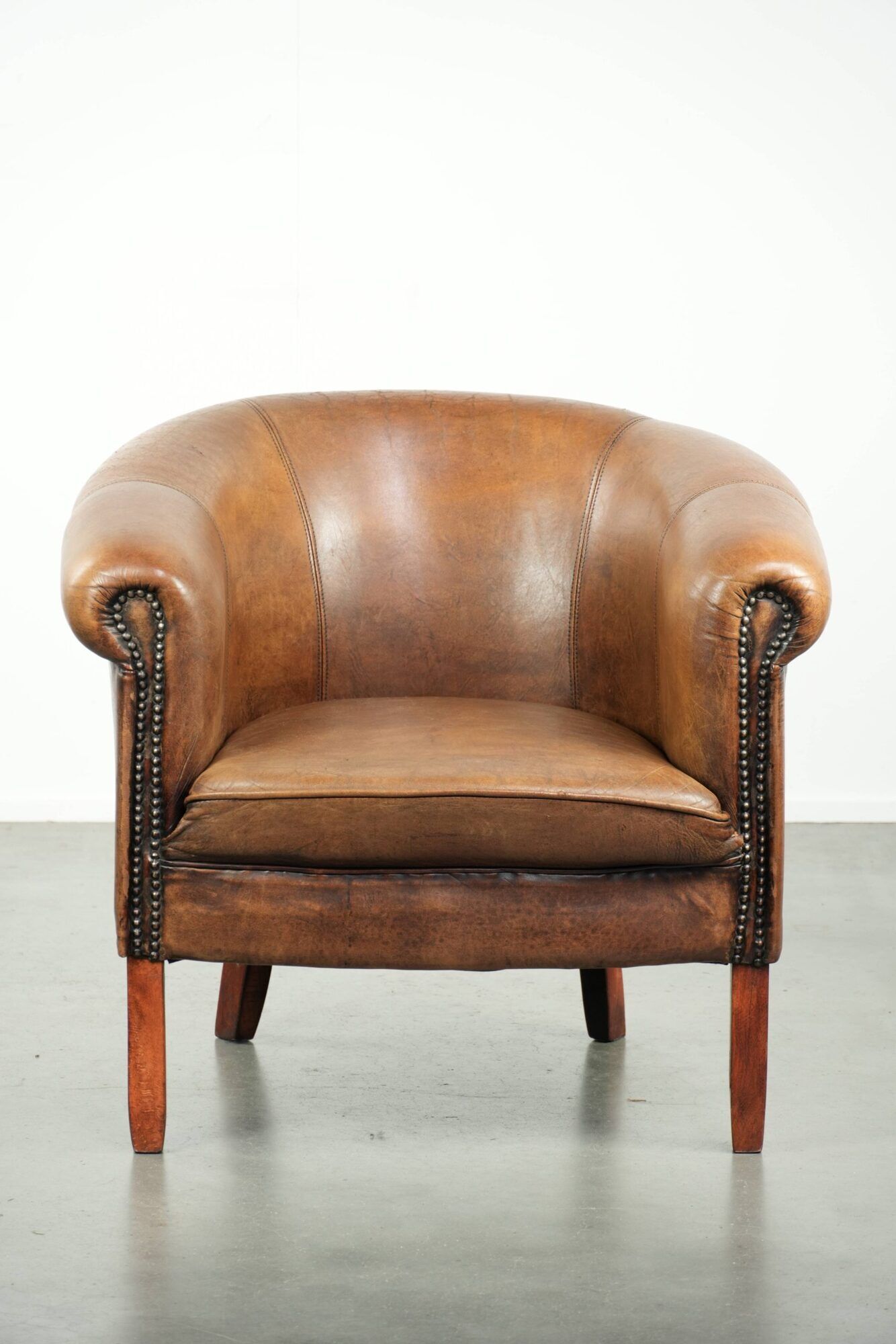 Sheepskin club armchair in a brown colour finished with decorative nails