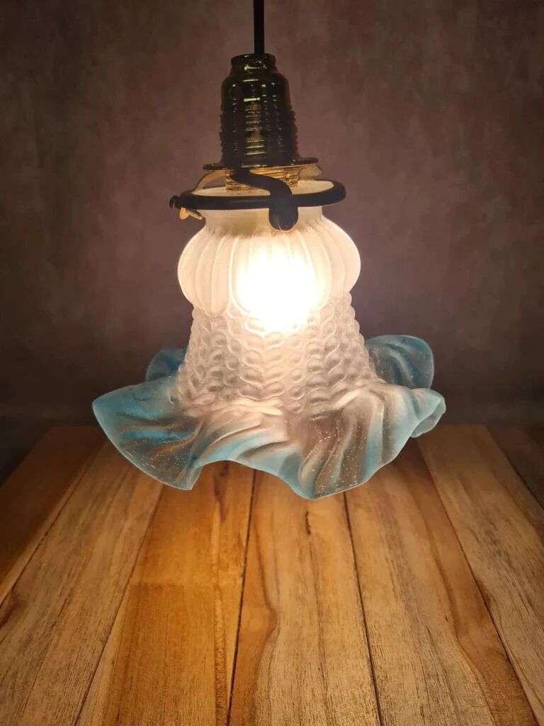 An antique lampshade in frosted glass with delicate blue edges.