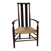 Fauteuil Arts & Crafts en bois massif brun foncé, avec assise en jonc naturel et dossier haut.