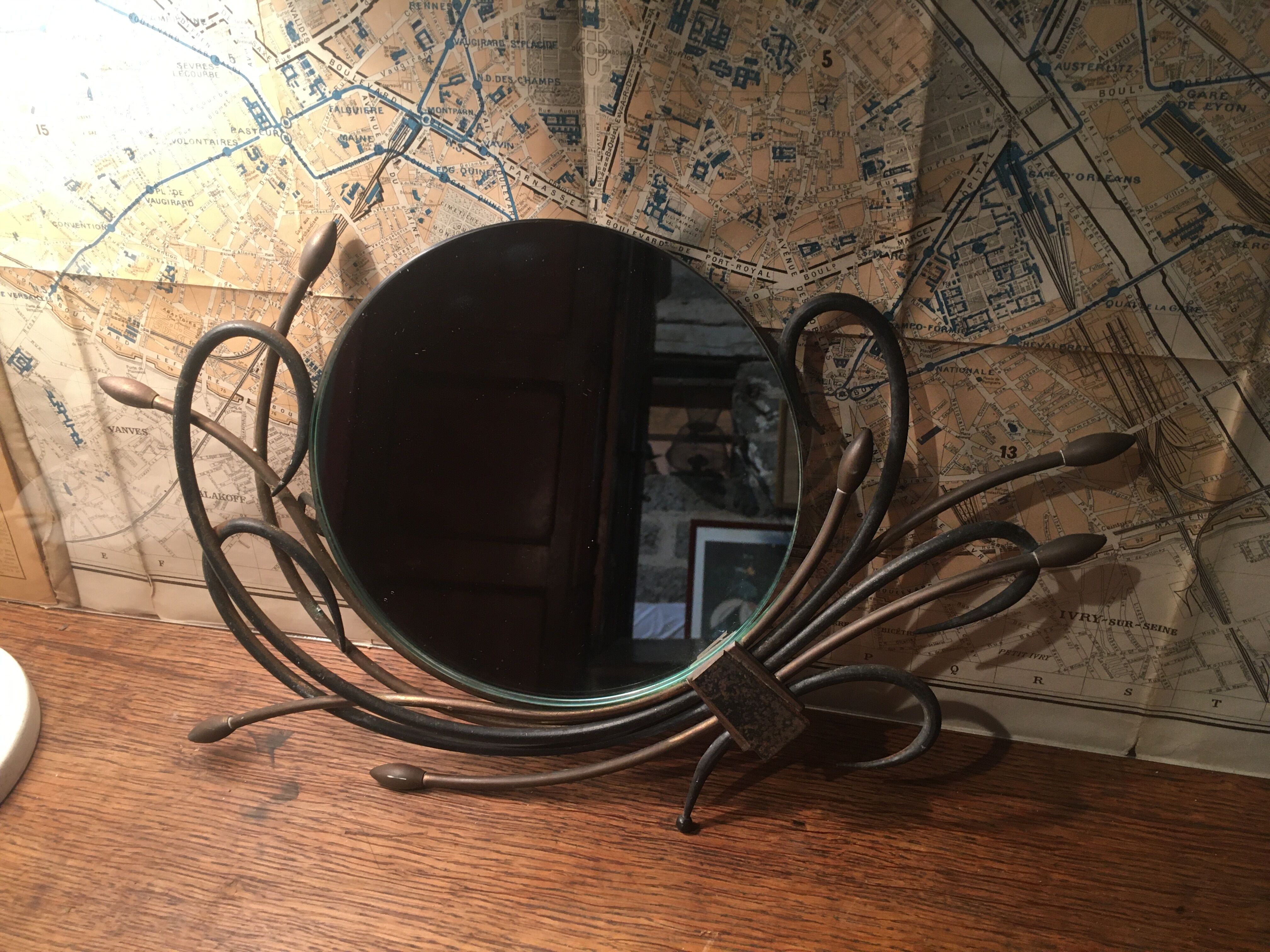 Round mirror surrounded by art deco style metal plants