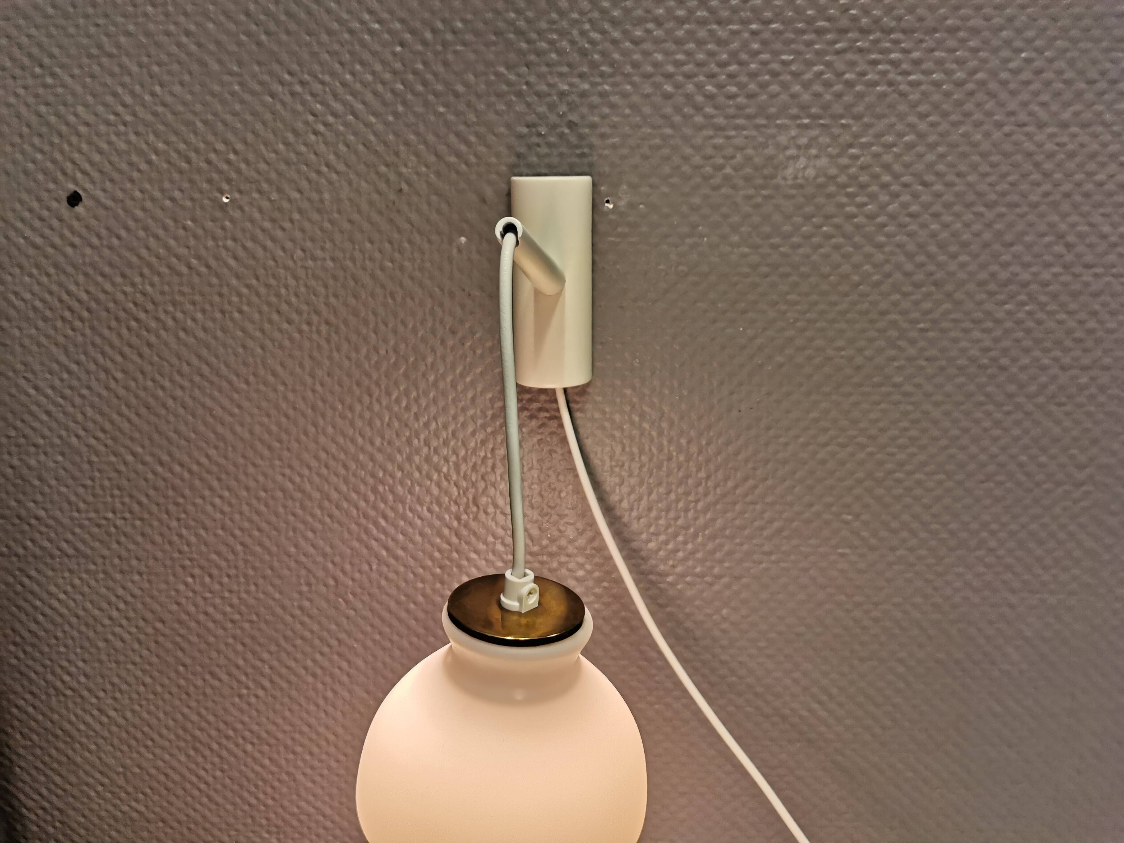 Milky white Holmegaard wall lamp with glass shade and a brass detail on top. Wooden wall bracket