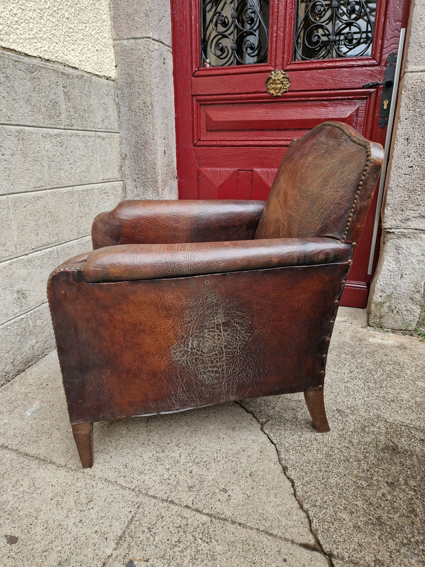 Antique club chair in patinated brown leather, early 20th century English style.
