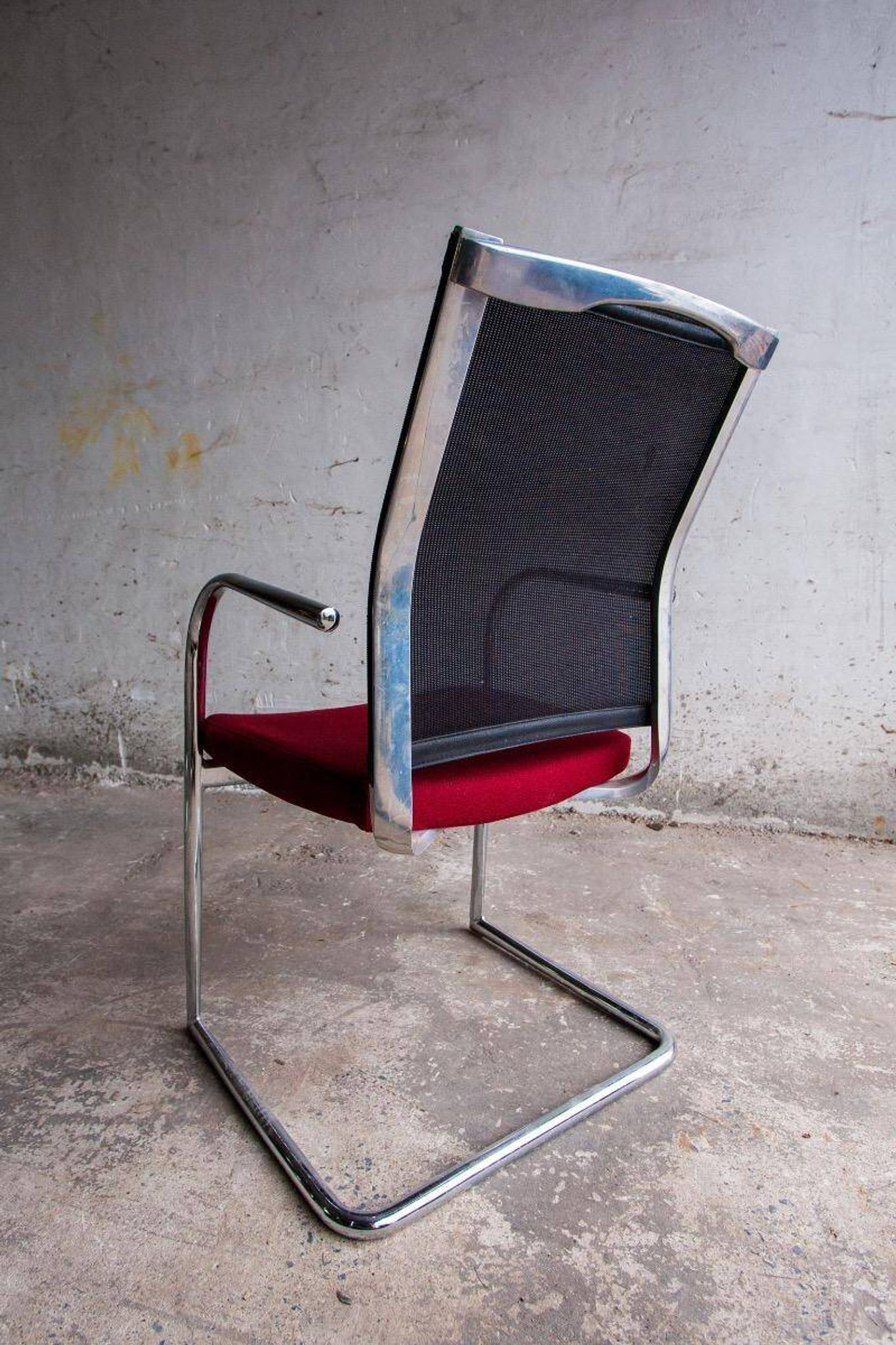 Set of 4 cantilever chairs with burgundy seat and mesh backrest.