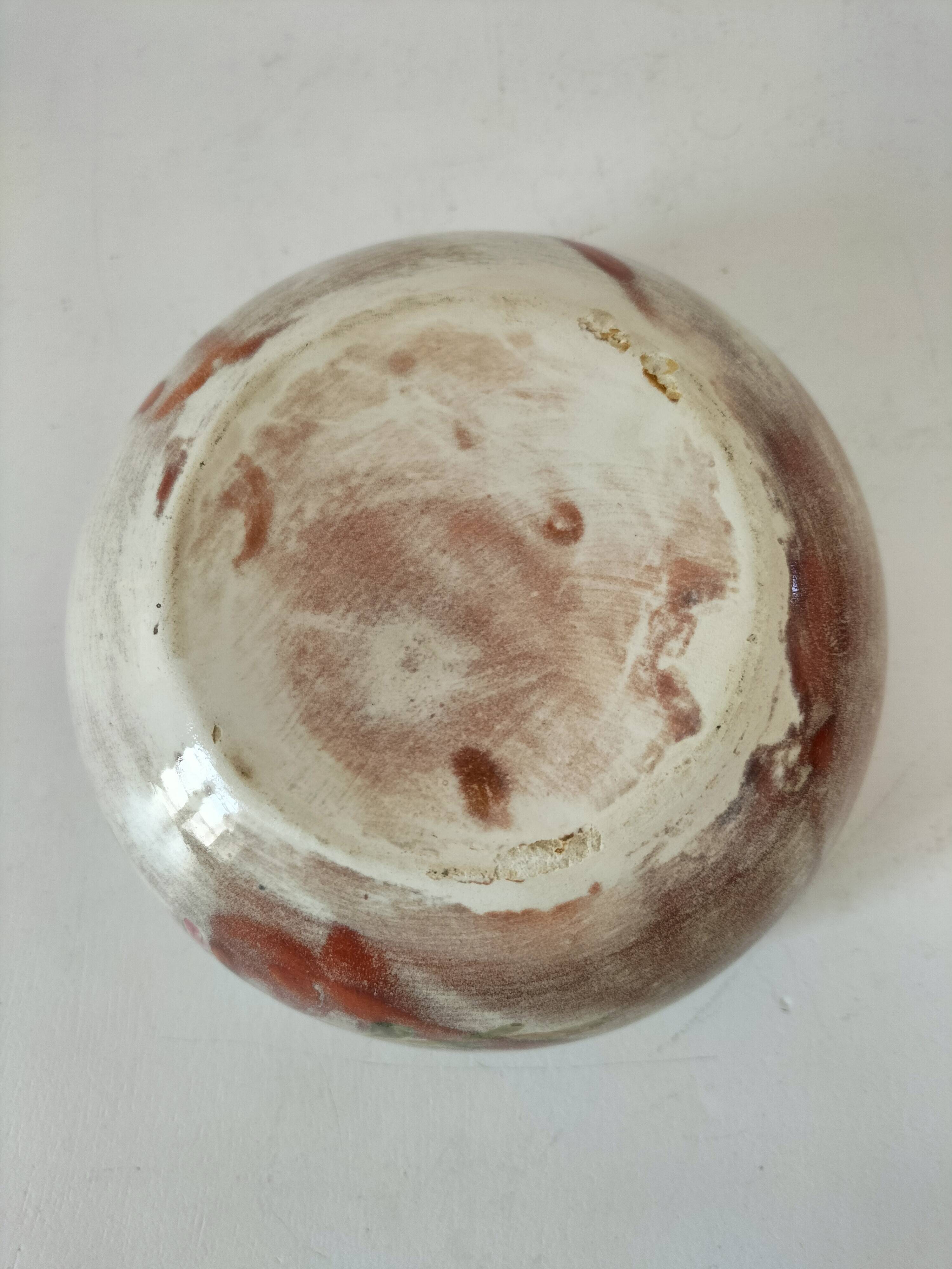 Red-orange glazed ceramic workshop bowl with floral decoration.