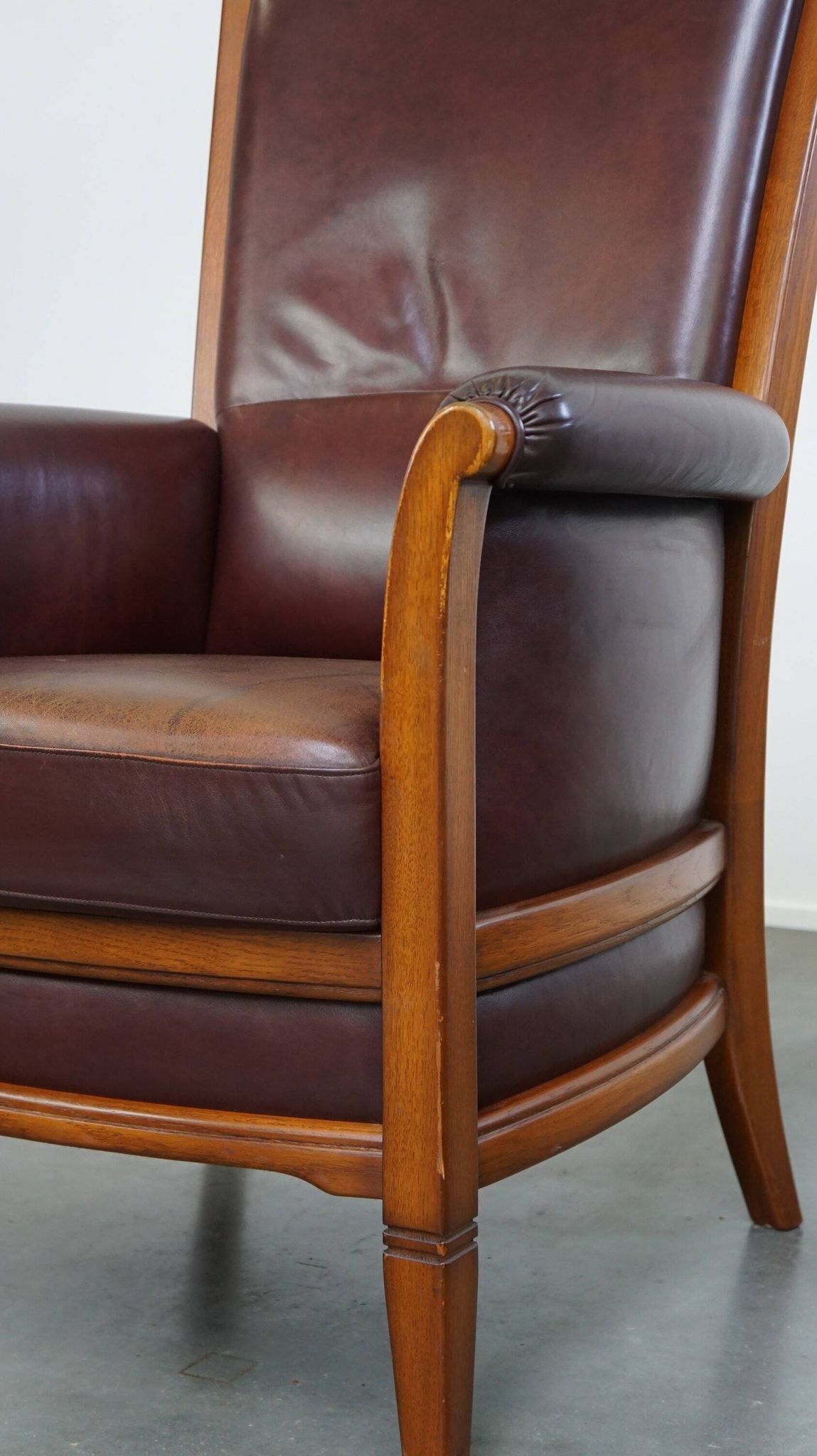 Very comfortable classic cowhide armchair with a high back in a mild Art Deco style