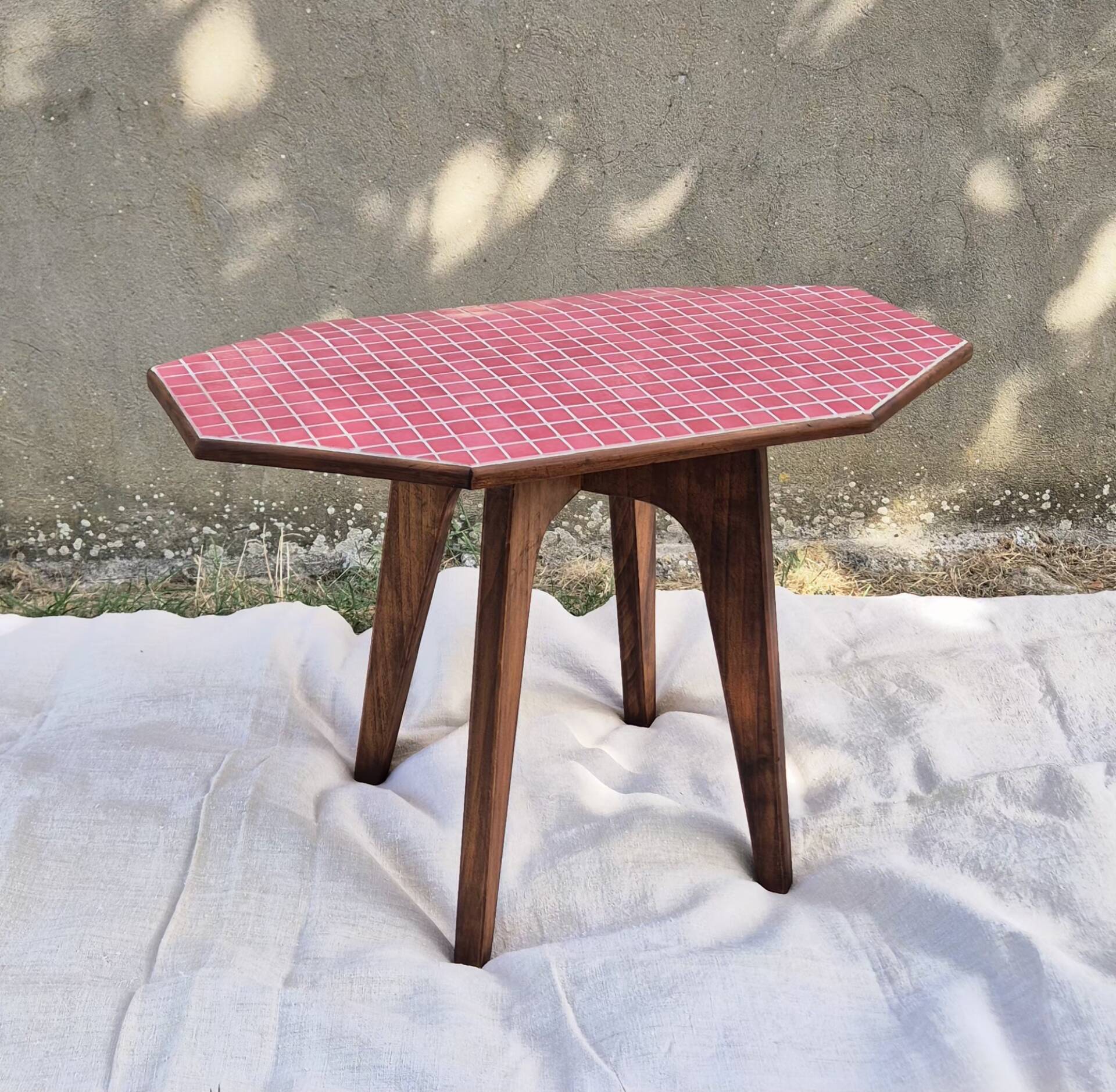 Small Scandinavian side table with wood and pink tiles, with tapered legs.