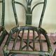 Round rattan table with glass top and 4 green rattan chairs.