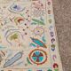 White suzani kilim rug with embroidered multi-colored patterns