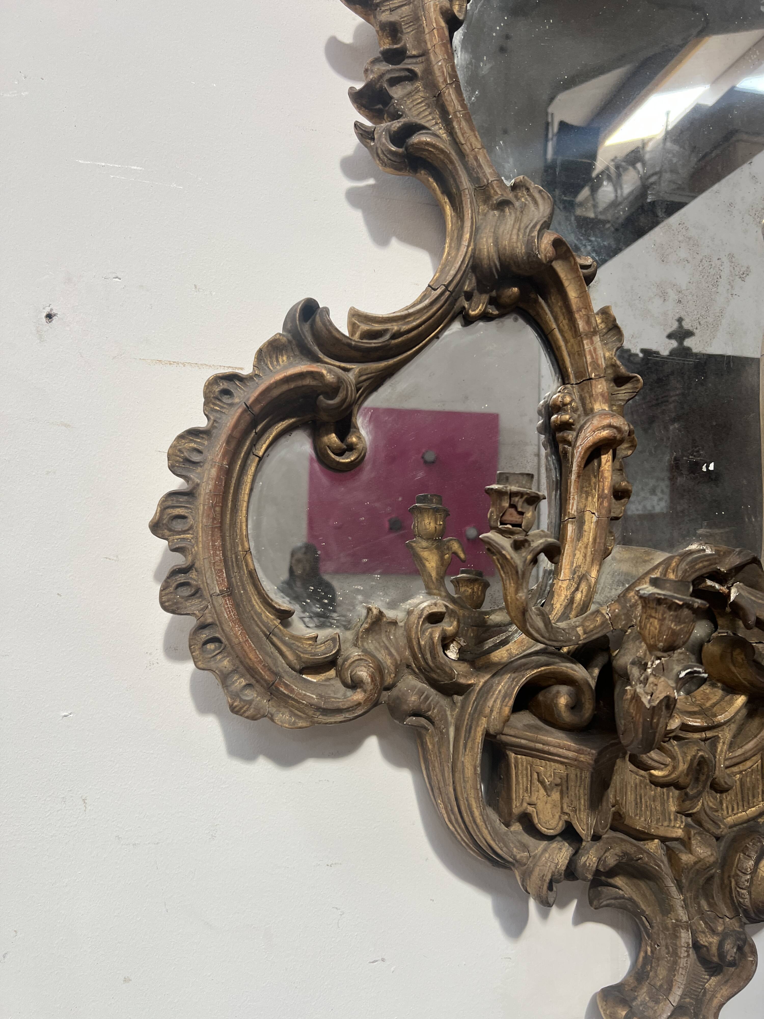 Mirror with a decorative frame featuring a four-light wall sconce, 19th century.