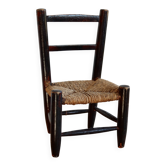 Small antique wooden child's chair with a straw seat.