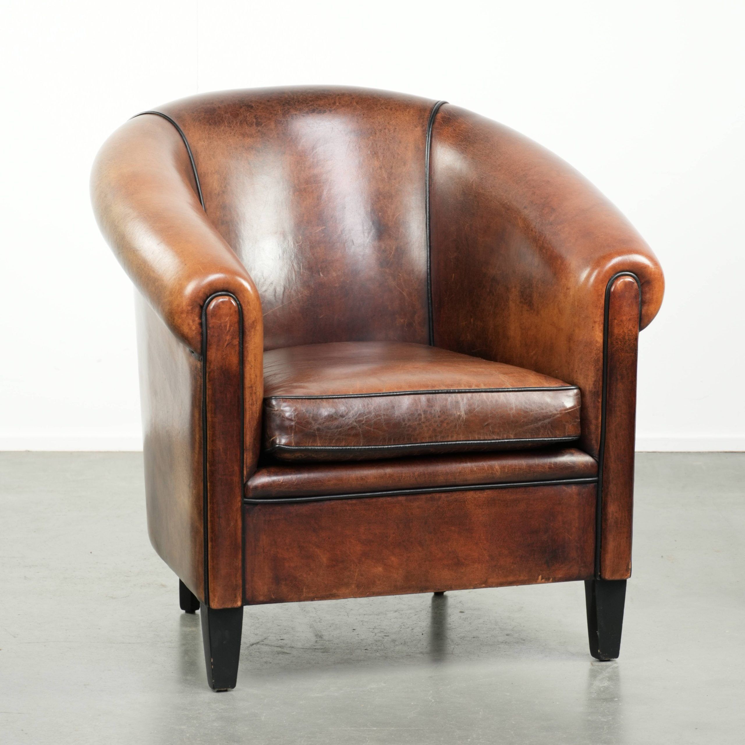 Sheepskin club armchair with deep warm colours and black piping