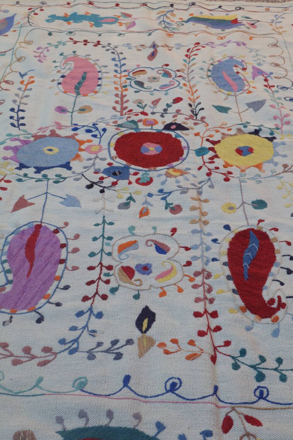 White suzani kilim rug with hand embroidered multi-colored patterns
