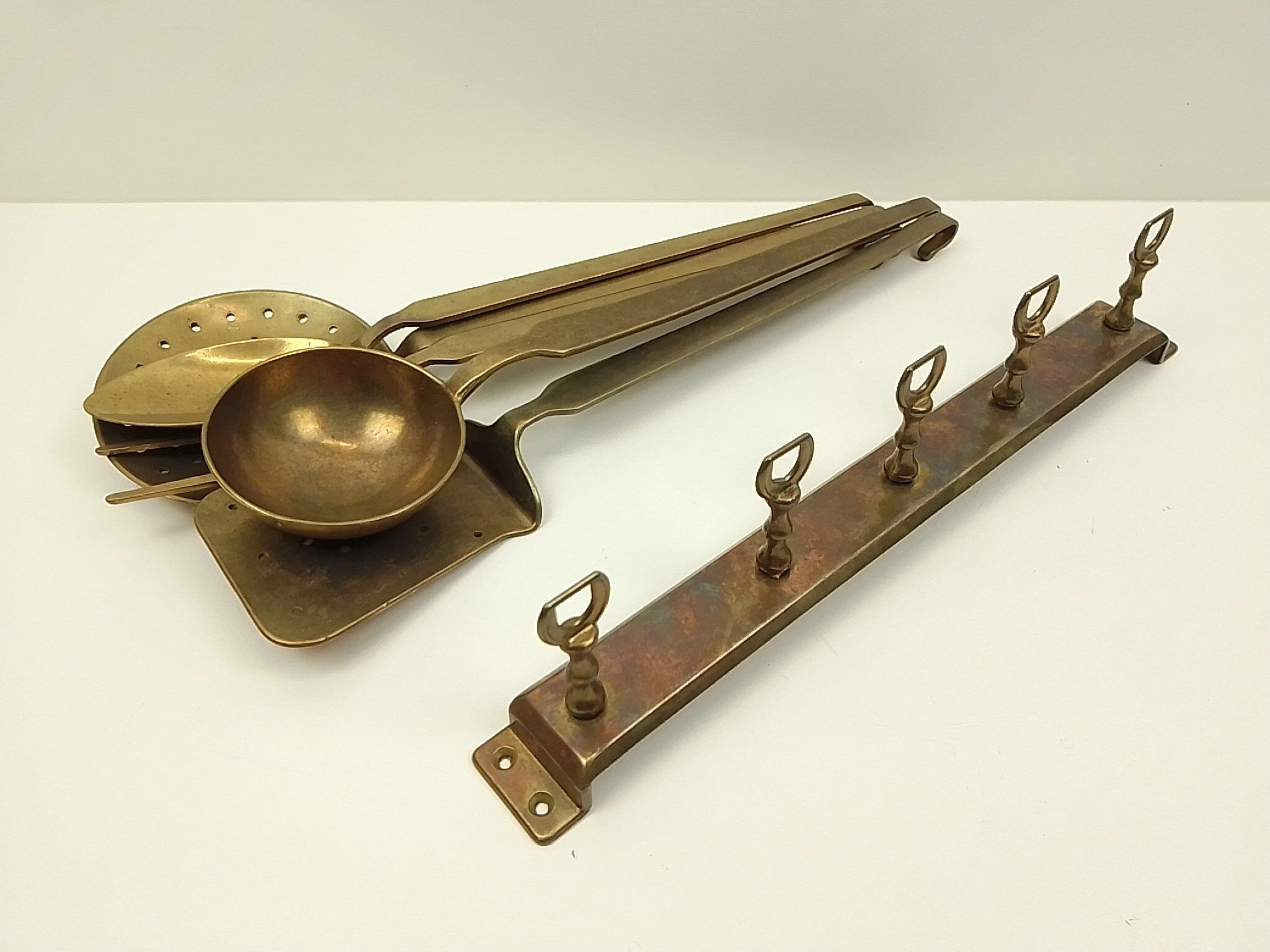 5 kitchen utensils and a brass wall mount
