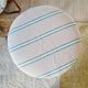 Antique stool with a wooden frame and a cream and green striped fabric seat.