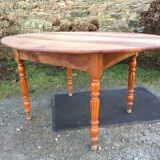 Table ovale ancienne en cerisier à piétement parapluie.