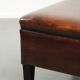 Large dark brown square ottoman made of sheepskin with black piping