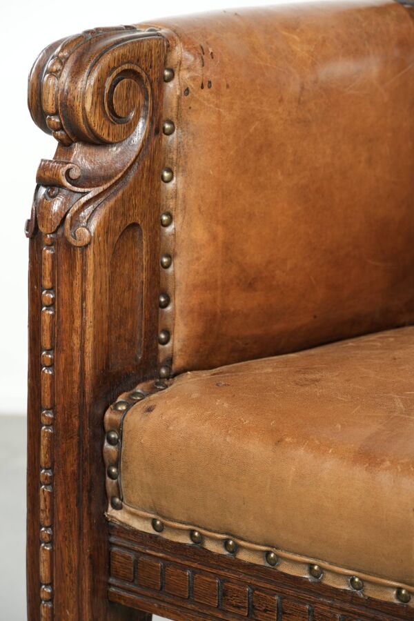 Fauteuil ancien en peau de mouton et bois avec des clous décoratifs.