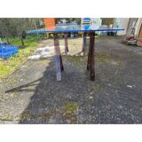 Vintage table with a glass top and smoked plastic trestle legs.