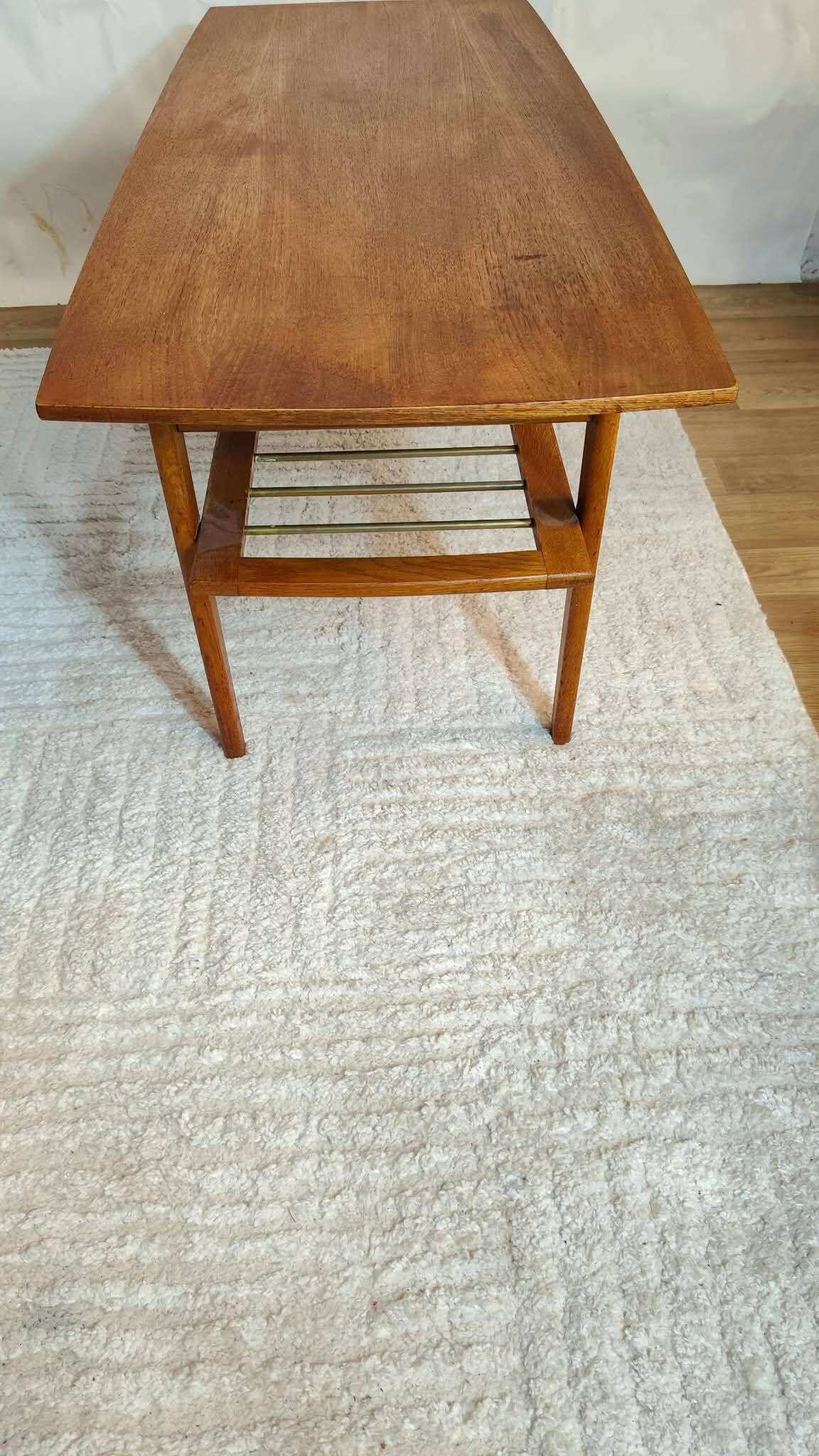 Scandinavian coffee table in teak with a lower shelf and brass bars.