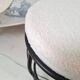 Black iron stool/pouf with its boucle fabric cushion.