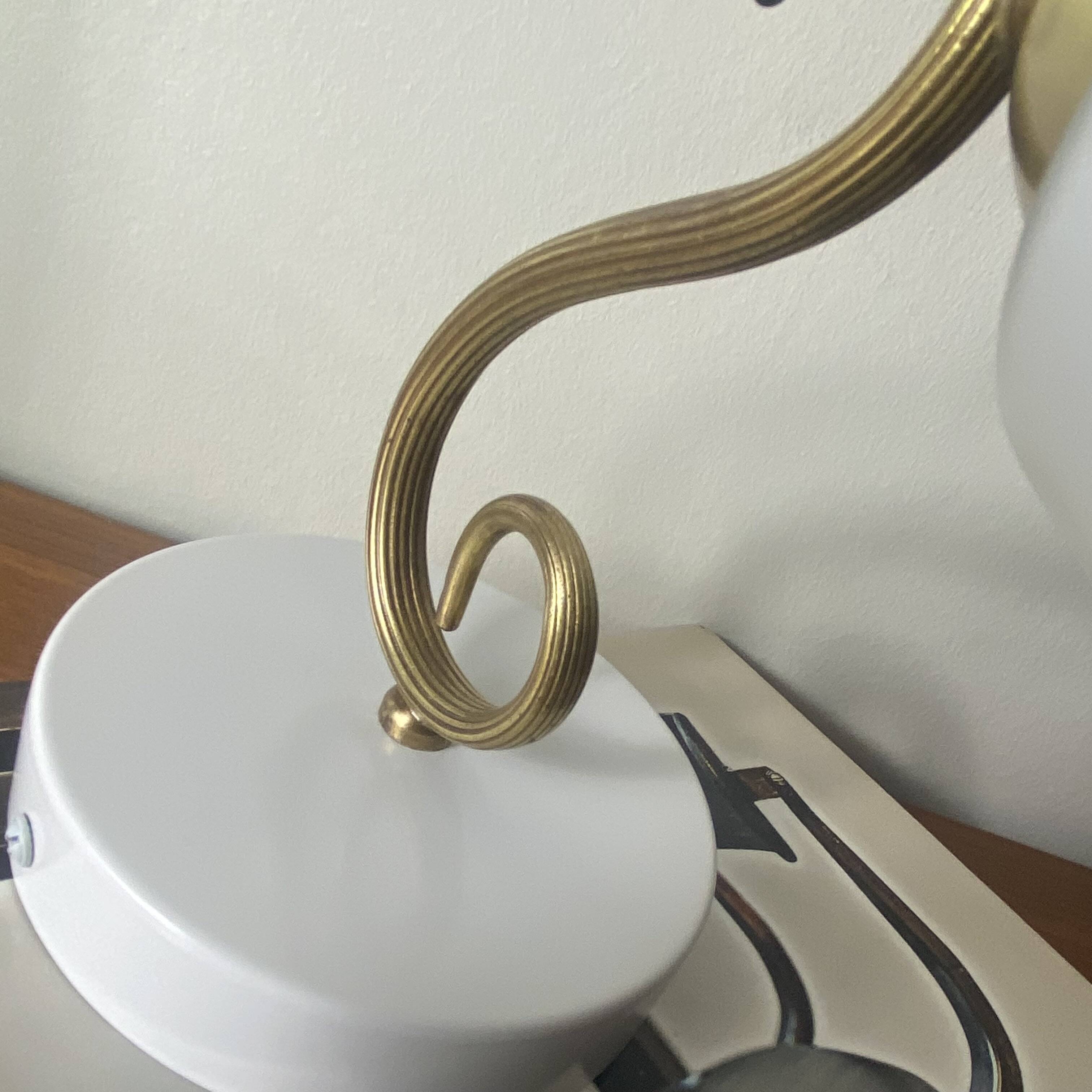 Swan neck wall light in brass with a white glass shade.