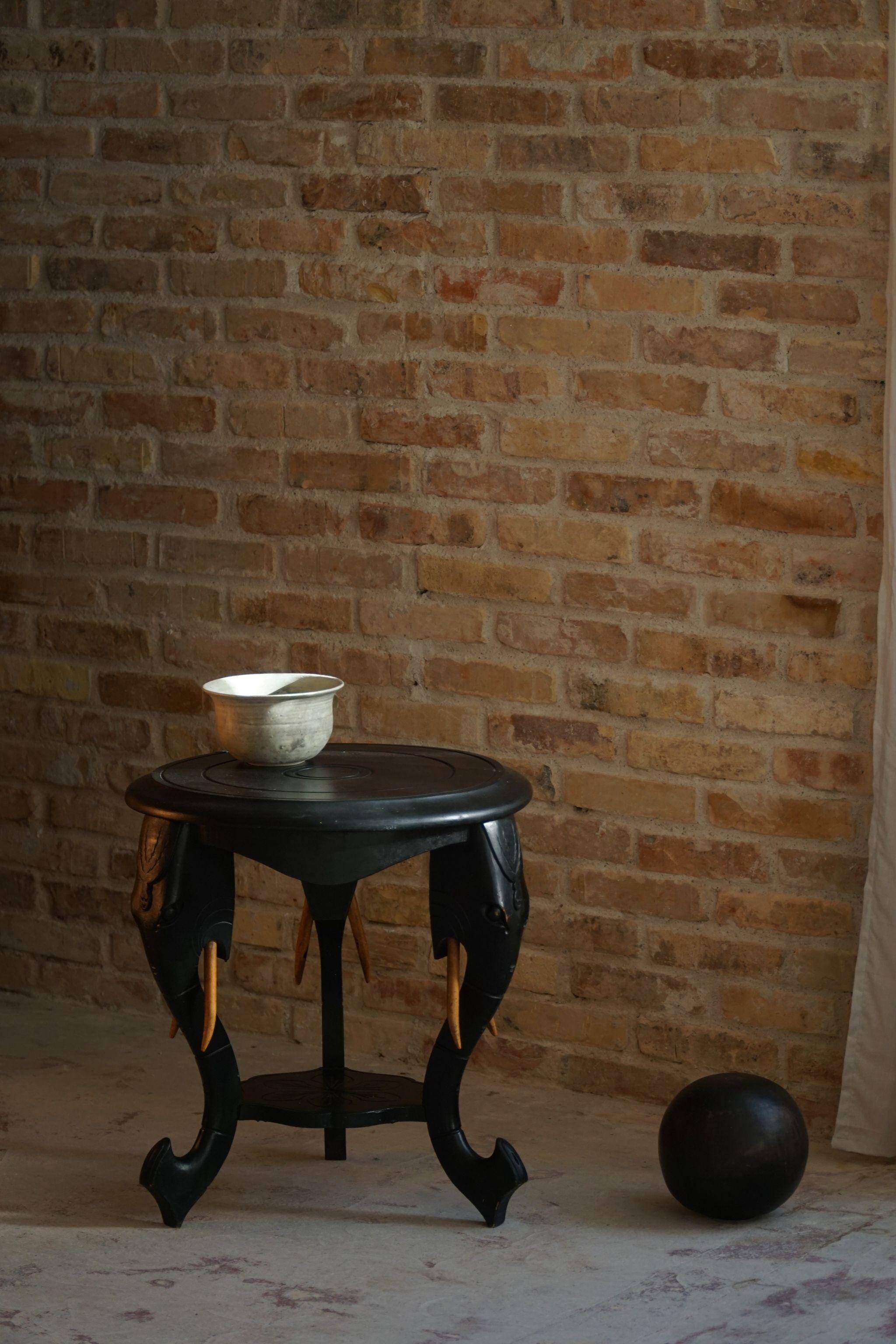 Side table in hardwood ebony with three elephant head-shaped legs, Eastern India, 1920s.
