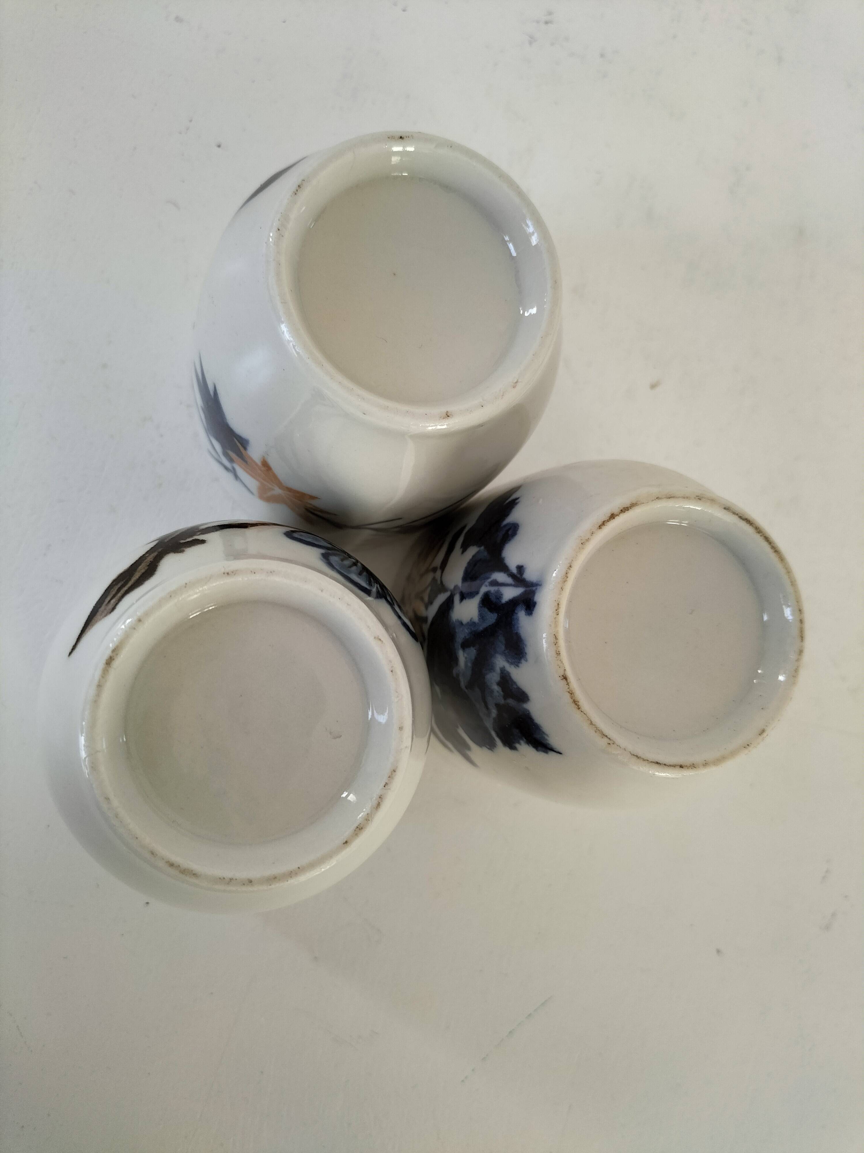 Set of three hand-painted porcelain cups with floral patterns.