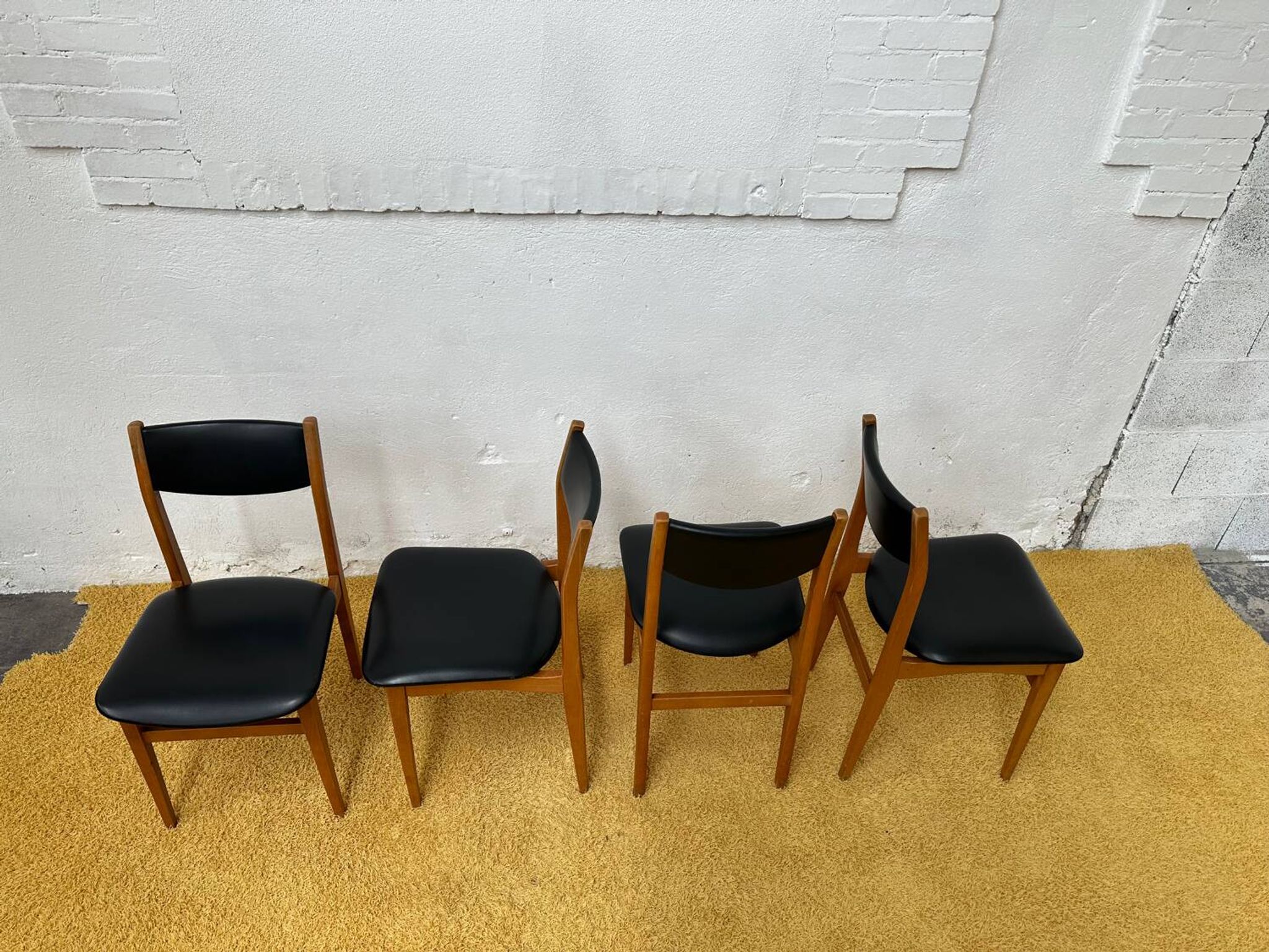 4 Scandinavian chairs in teak and black faux leather.