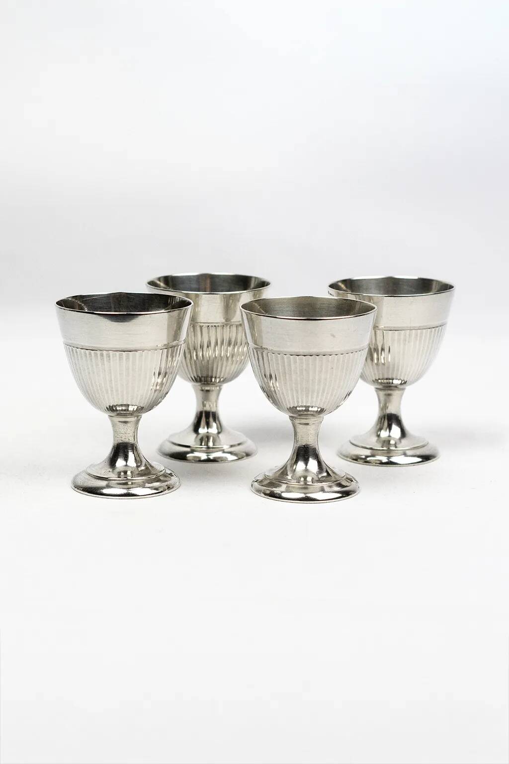 Four silver-plated Christofle egg cups with fluted sides.