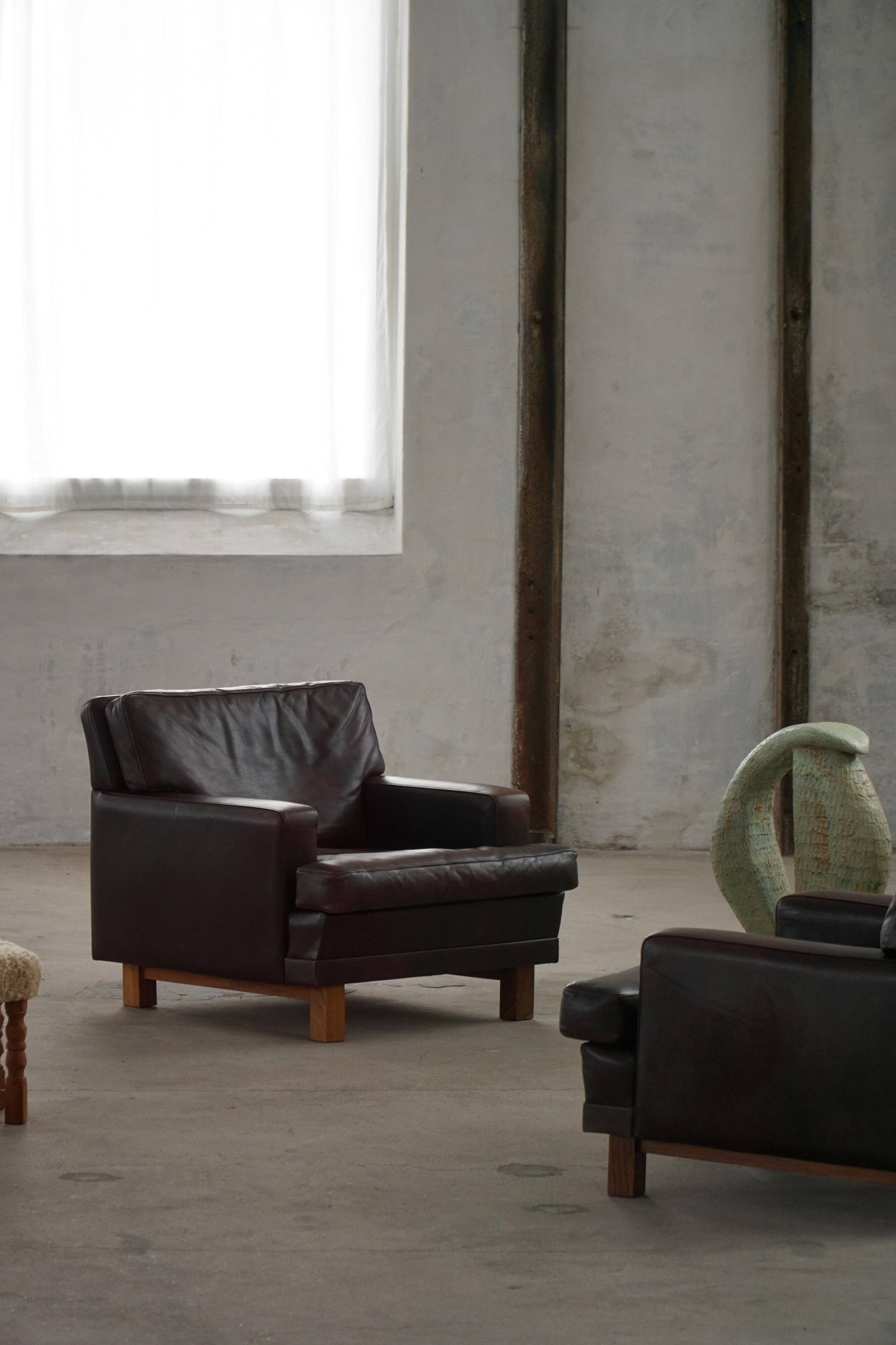 Pair of modern Danish lounge chairs in dark brown leather and rosewood, 1960s.