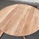 Large extendable round dining table stripped in solid cherry wood with a central leg.
