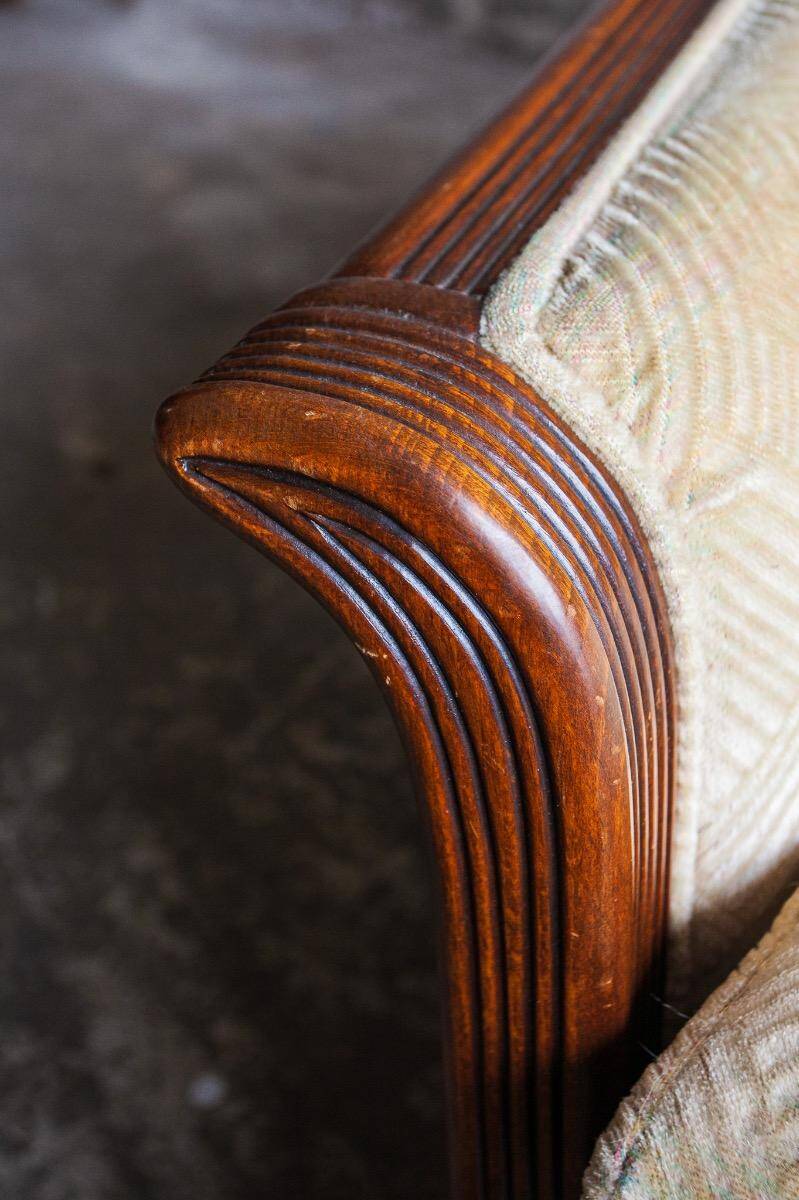 Two-seater Art Deco sofa with ornate wooden details.
