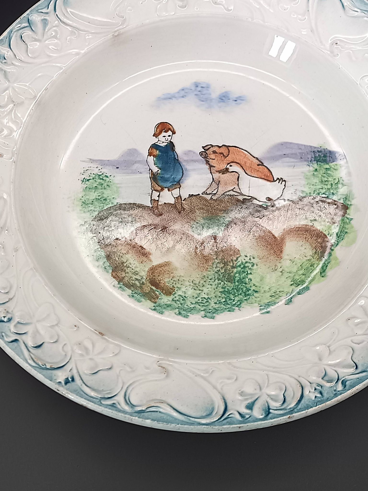 Large antique hollow dish from the 19th century, earthenware with pastoral decoration featuring a child, pig, and goose.