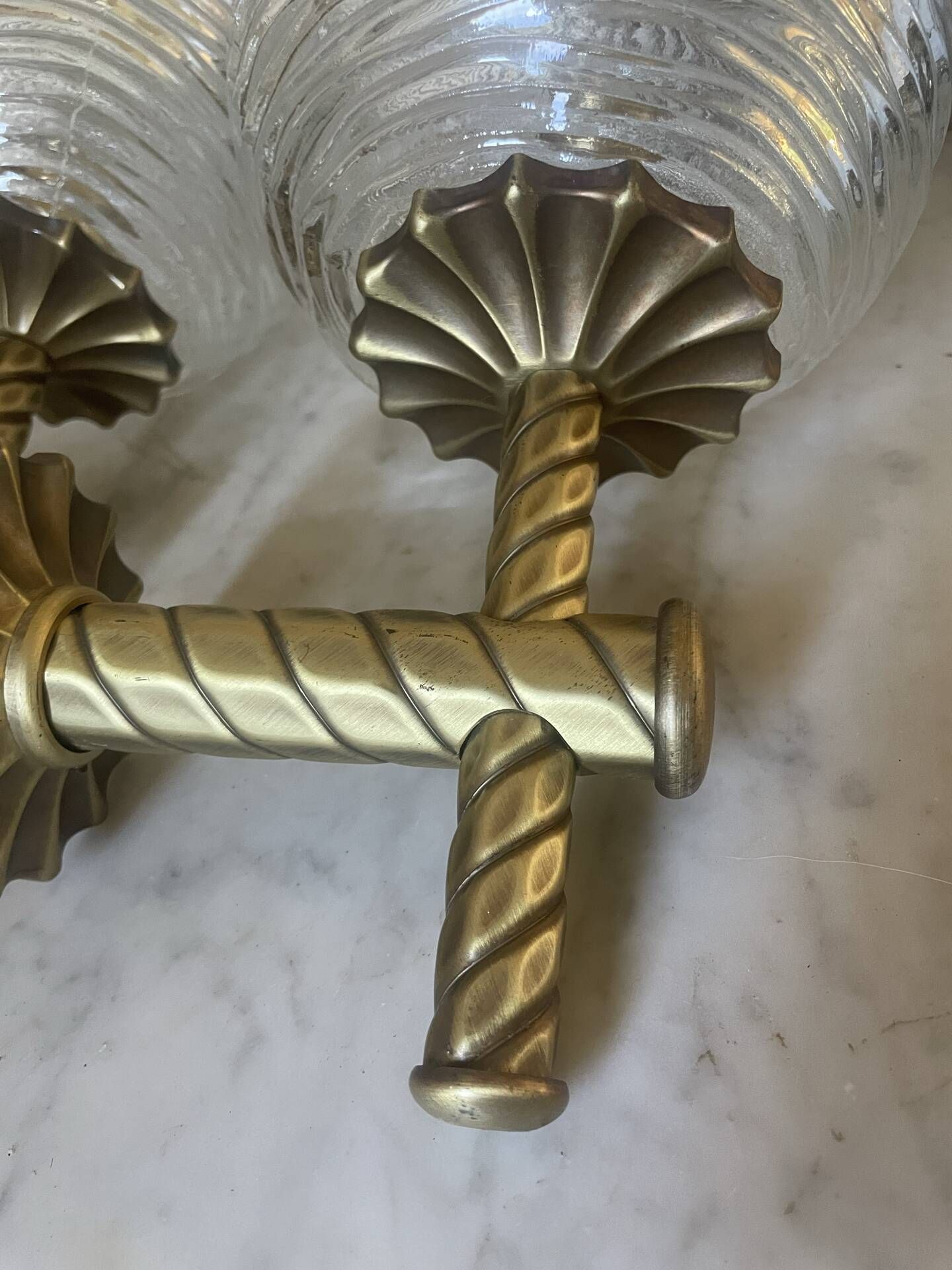 Pair of neoclassical wall sconces in twisted brass and ribbed glass.